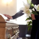 Person placing hand on coffin
