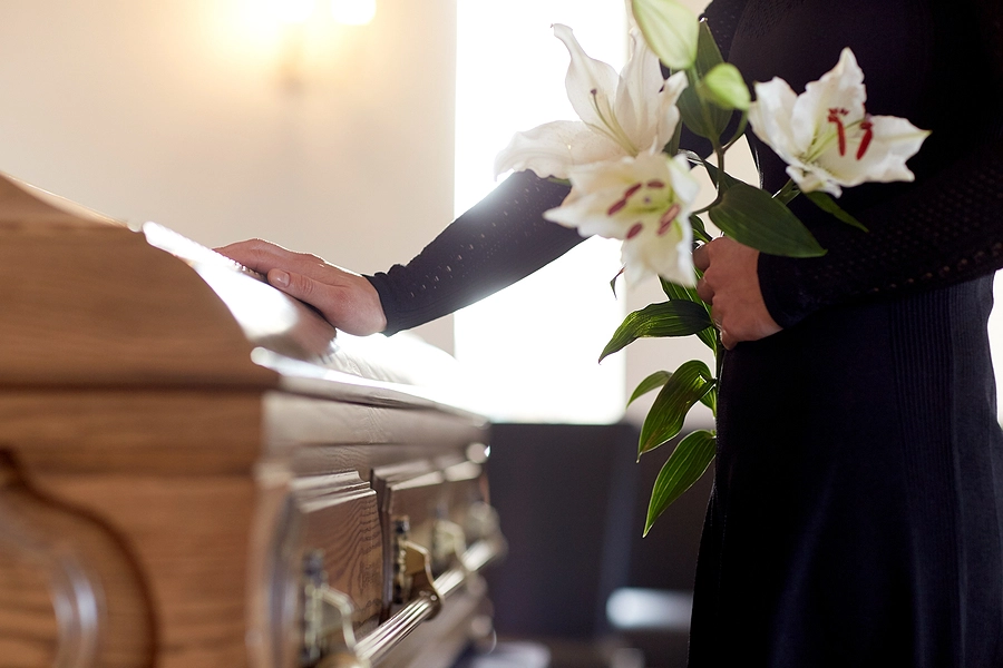Person placing hand on coffin